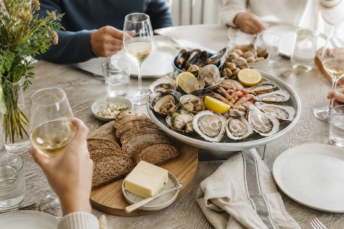 Convives partageant un plateau de coquillages avec pain de seigle et beurre